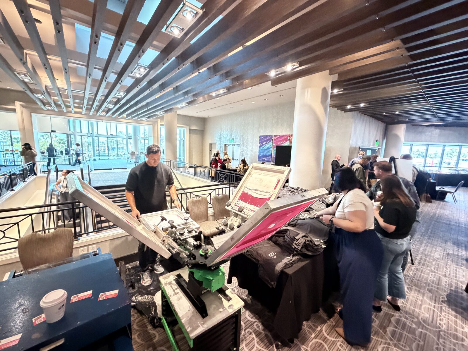 Four-color press running at a hotel conference with guests lining up beside it